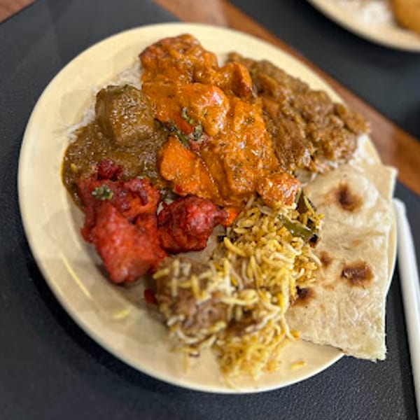 A plate of Daddy's Indian Cuisine with chicken tikka masala, biryani, tandoori chicken, and naan.
