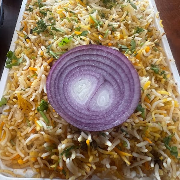 Daddy's Indian Cuisine biryani, a flavorful rice dish with herbs and a red onion slice.
